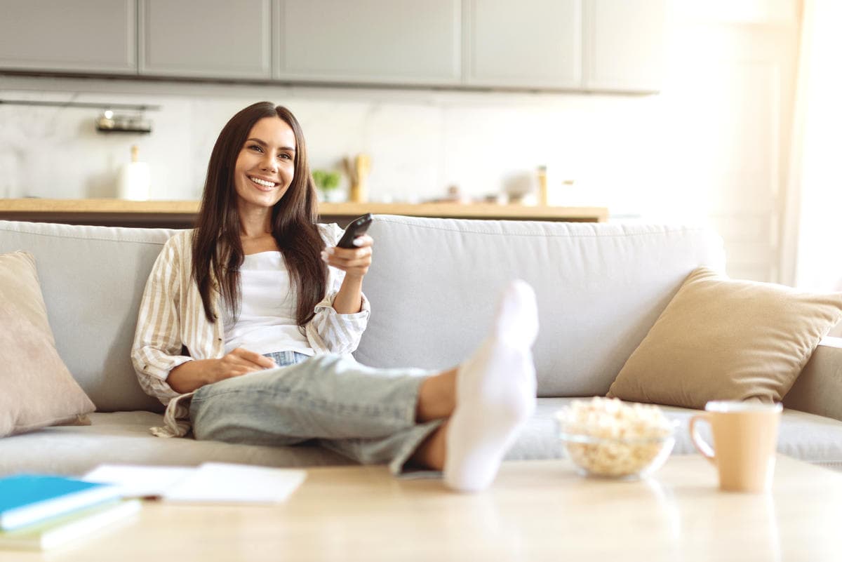 Person relaxing on a sofa in a clean, organized living room, representing confidence and ease supported by thoughtful home care and product recommendations.