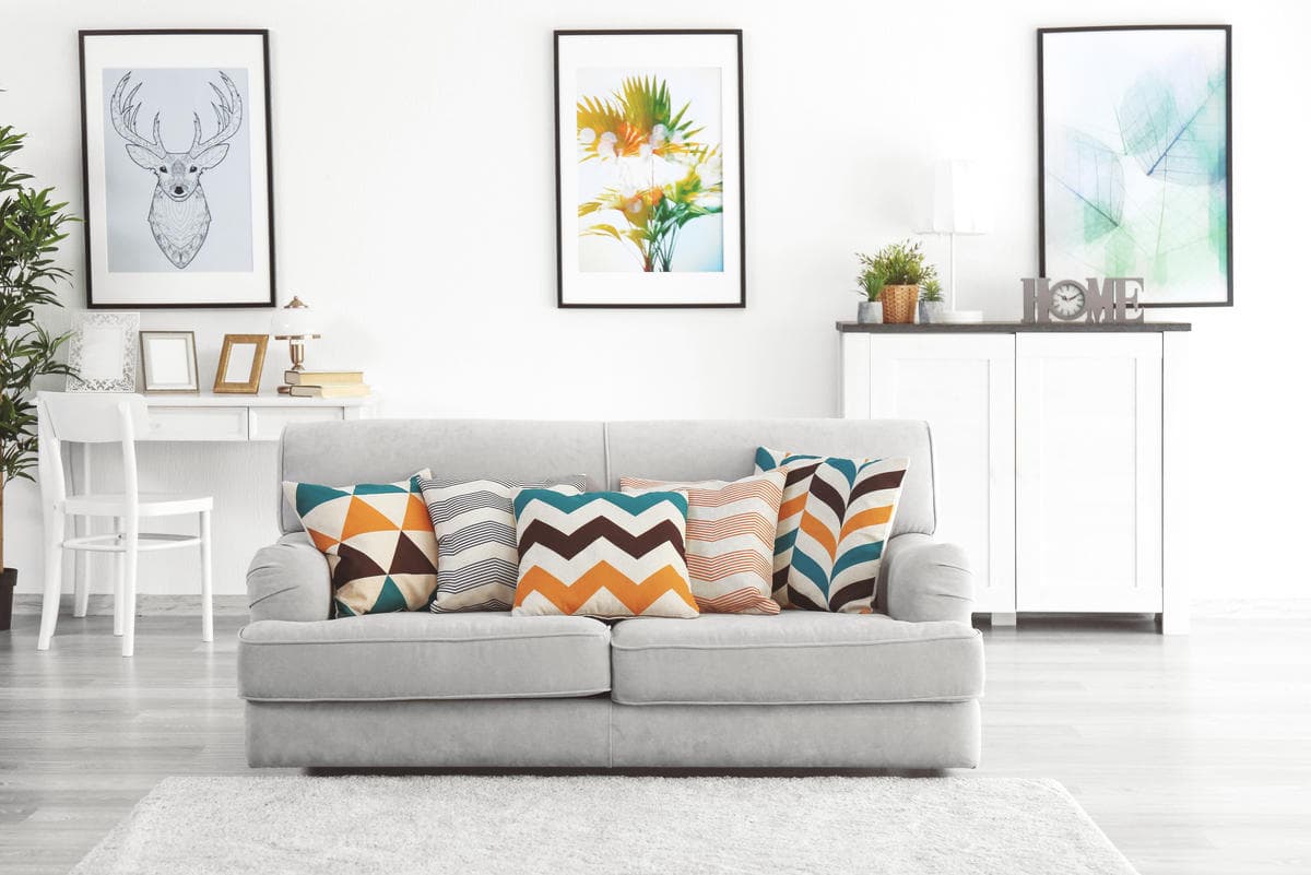 Bright living room with sofa and pillows, room-by-room cleaning basics for a tidy space.