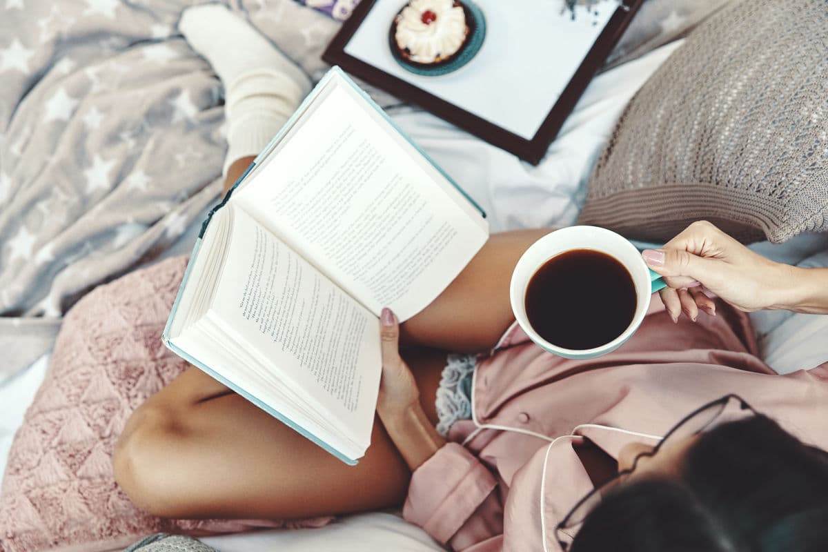 Person reading a book with coffee, stories and insights from the cleaning journal.