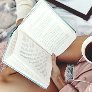 Person reading a book with coffee, stories and insights from the cleaning journal.